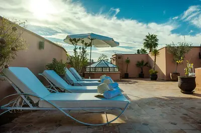 a group of blue lounge chairs and an umbrella on a patio at Riad Nasreen in Marrakech