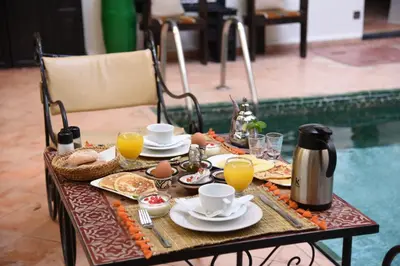 a table with breakfast foods and orange juice on it at Riad Du Petit Prince in Marrakech