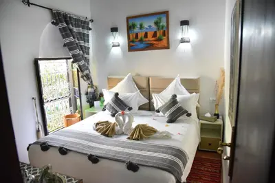 a bedroom with a bed with white sheets and a window at Riad Du Petit Prince in Marrakech