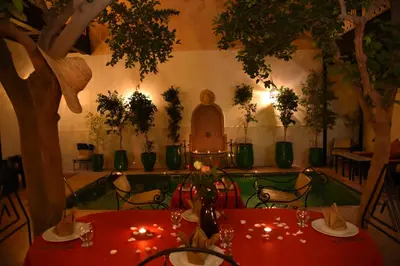 a restaurant with two tables and a statue in the background at Riad Du Petit Prince in Marrakech