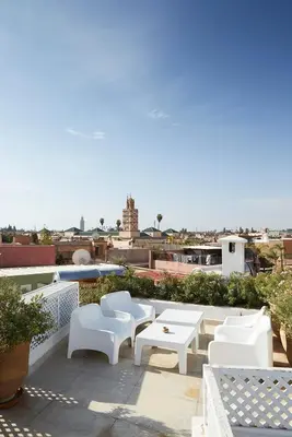 a group of white chairs and tables on a roof at Riad O in Marrakech