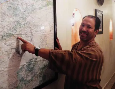 a man pointing to a map on a wall at Riad Linda in Marrakech