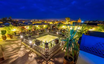 a balcony with a view of a city at night at Riad Nesma Suites & Spa in Marrakech