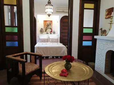 a room with a bed and a table and a fireplace at Riad Dar Nouba in Marrakech
