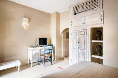 a bedroom with a bed and a desk with a television at Riad Le Rihani in Marrakech