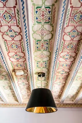 a lamp in front of a ceiling withpainted ceilings at Riad Le Rihani in Marrakech