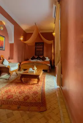 a bedroom with two beds and a table in a room at Dar Sohane in Marrakech