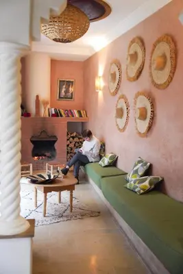 a man sitting on a couch in a living room with a fireplace at Monriad in Marrakech