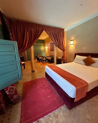 a bedroom with a large bed and a living room at Palais Riad Berbère in Marrakech