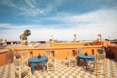 a patio with two tables and chairs on a roof at Hotel & Spa Dar Baraka & Karam in Marrakech
