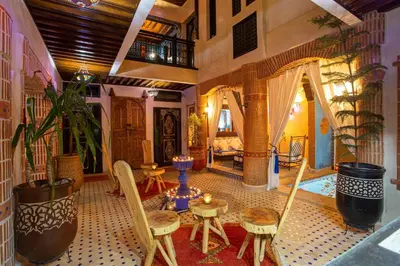 a living room with a table and chairs and a bedroom at Riad Christina in Marrakech
