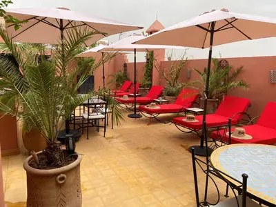 a patio with red chairs and tables and umbrellas at Riad Alboraq in Marrakech