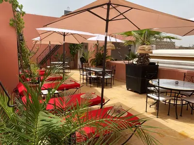 a patio with tables and chairs and an umbrella at Riad Alboraq in Marrakech