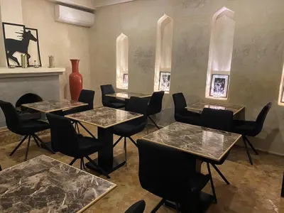 a room with tables and chairs and a fireplace at Riad Alboraq in Marrakech