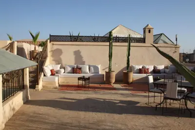 a patio with white couches and tables and plants at Riad Shama Suites & Spa in Marrakech