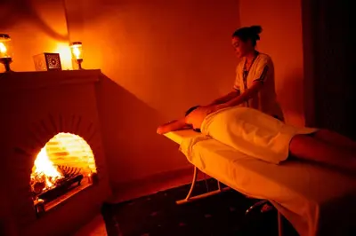 a woman standing next to a bed in a room with a fireplace at Riad Shama Suites & Spa in Marrakech