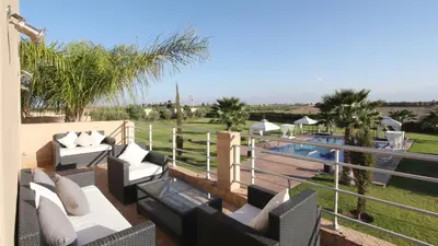 a patio with couches and a pool with palm trees at Palais Ambrine in Marrakech