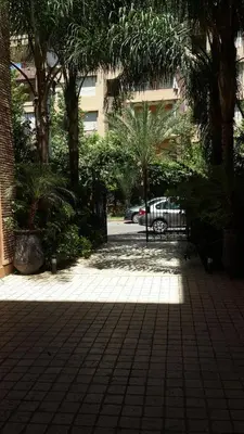 a shady courtyard with palm trees and a building at Ritaj Apartement in Marrakech