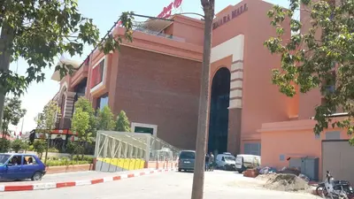 a pink building with cars parked in front of it at Ritaj Apartement in Marrakech