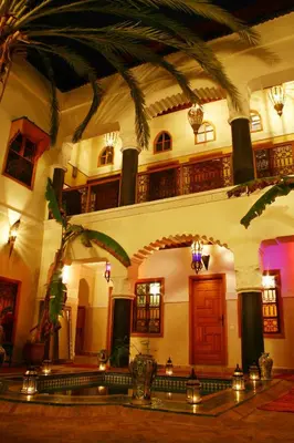 a large building with a palm tree in front of it at Riad Zanzibar in Marrakech