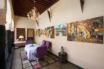 a room with a table with purple chairs and paintings at Riad Zanzibar in Marrakech