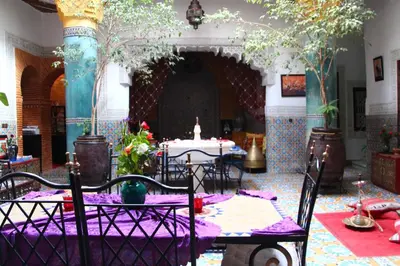 a room with a table and chairs in a building at Riad Bibtia in Marrakech