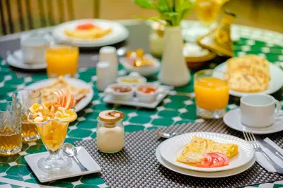 a table topped with plates of food and orange juice at Riad Amina in Marrakech
