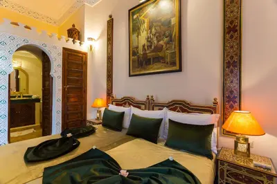 a bedroom with a bed and a painting on the wall at Riad Amina in Marrakech