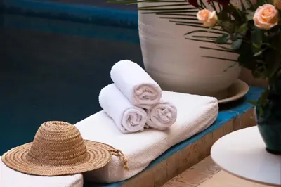 a hat and towels on a table with a vase at Riad Assala in Marrakech