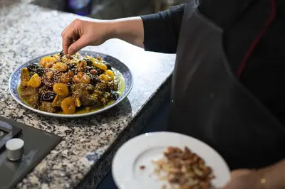 a person preparing a plate of food on a counter at Riad Assala in Marrakech