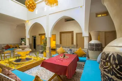 a living room with a red table and blue chairs at Riad El Kennaria in Marrakech