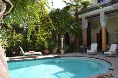 a swimming pool in a yard with chairs and a house at Palais El Arsat & Spa in Marrakech