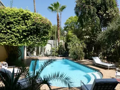 a swimming pool in a yard with palm trees at Palais El Arsat & Spa in Marrakech