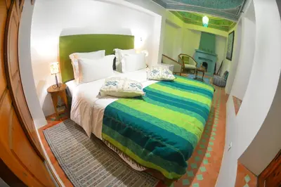 a bedroom with a large bed with a green headboard at Riad Hidden in Marrakech