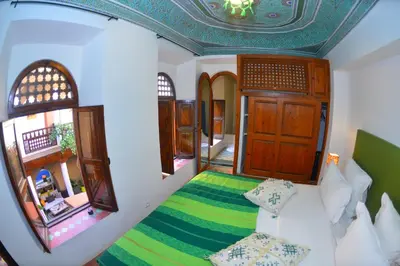 a bedroom with a bed with a green blanket at Riad Hidden in Marrakech