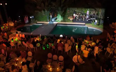 a group of people sitting around a pool at night at Villa Des 3 Golfs in Marrakech