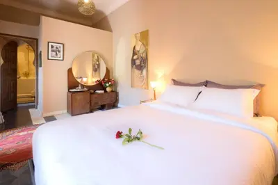 a bedroom with a large white bed with a flower on it at Riad Adrar in Marrakech