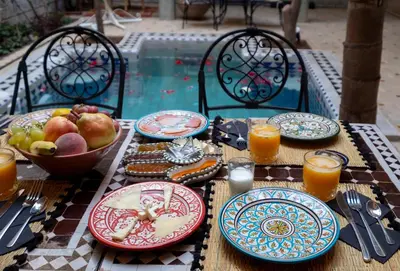 a table with plates of food and a bowl of fruit at Riad Adrar in Marrakech