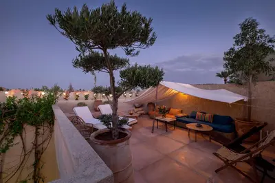 a patio with a tree and a couch and chairs at Riad Adrar in Marrakech