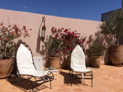 two chairs sitting in front of a wall with flowers at Riad Irene in Marrakech