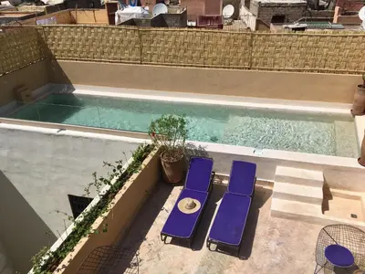 two blue lounge chairs sitting next to a swimming pool at Riad Houdou in Marrakech