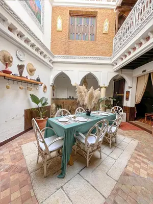 a dining room with a green table and chairs at Riad Elli Marrakech in Marrakech
