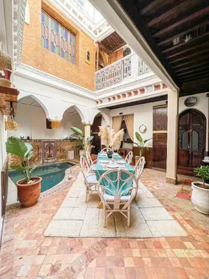 a patio with a table and chairs and a pool at Riad Elli Marrakech in Marrakech