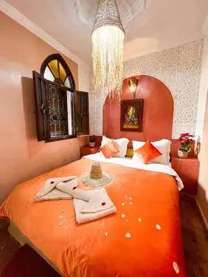 a bedroom with a large orange bed with towels on it at Riad Elli Marrakech in Marrakech