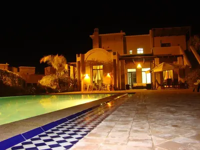 a swimming pool in front of a house at night at Marrakech Pearl in Marrakech
