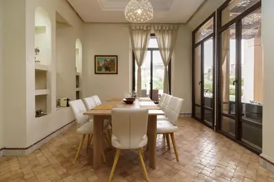 a dining room with a wooden table and white chairs at Marrakech Pearl in Marrakech