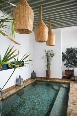 a swimming pool in a house with potted plants at Riad Danka in Marrakech