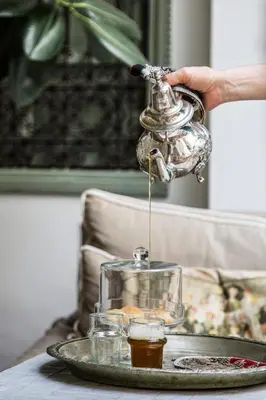 a person holding a tea kettle on a table at Riad Danka in Marrakech