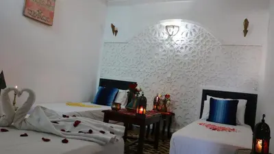 a bedroom with two beds and a table with a candle at Dar Habache in Marrakech