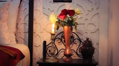 a vase of flowers on a table with a candle at Dar Habache in Marrakech